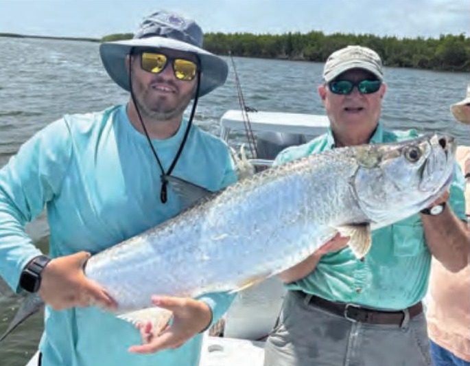 Two anglers holding a tarpon