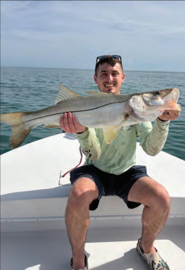 Angler holding a snook on a Yellow Dawg Fishing charter near Ponce Inlet