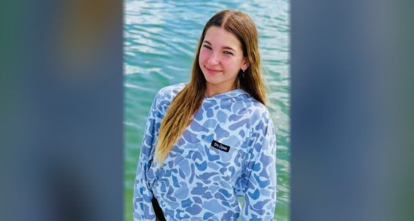 Young angler in a Sol Fishing performance shirt standing in shallow water