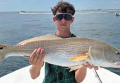 Young angler holding a redfish on a Yellow Dawg Fishing charter near Ponce Inlet
