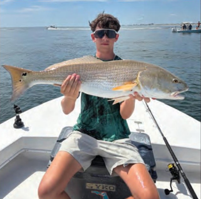 Young angler holding a redfish on a Yellow Dawg Fishing charter near Ponce Inlet