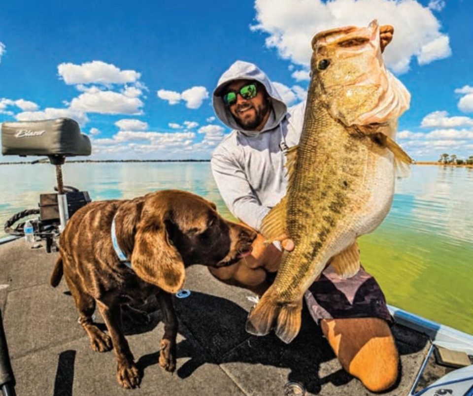 Capt. Tyler Woolcott with a big largemouth bass and his chocolate lab