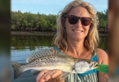 An angler holding a spotted seatrout in front of the mangroves