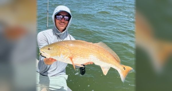 Capt. Austin Ferguson of Ferg's Guide Service holding a redfish on his boat