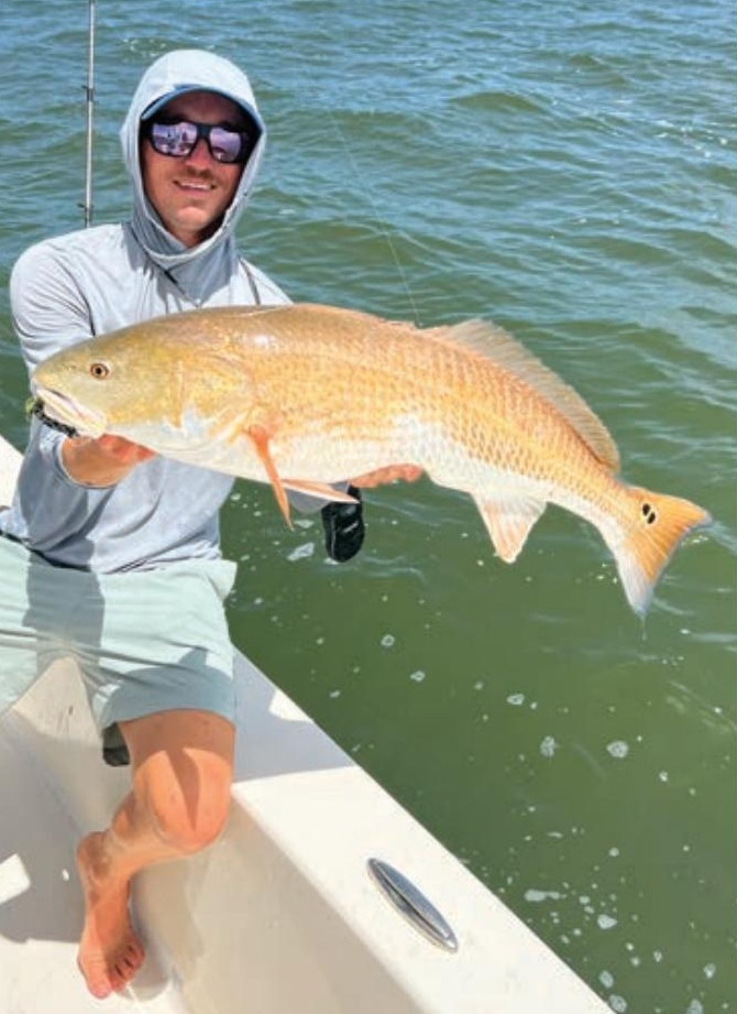 Capt. Austin Ferguson of Ferg's Guide Service holding a redfish on his boat