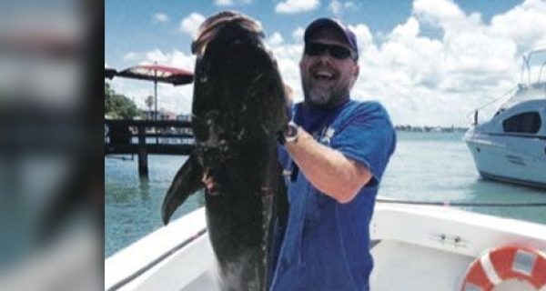 Angler holding a large fish on a boat