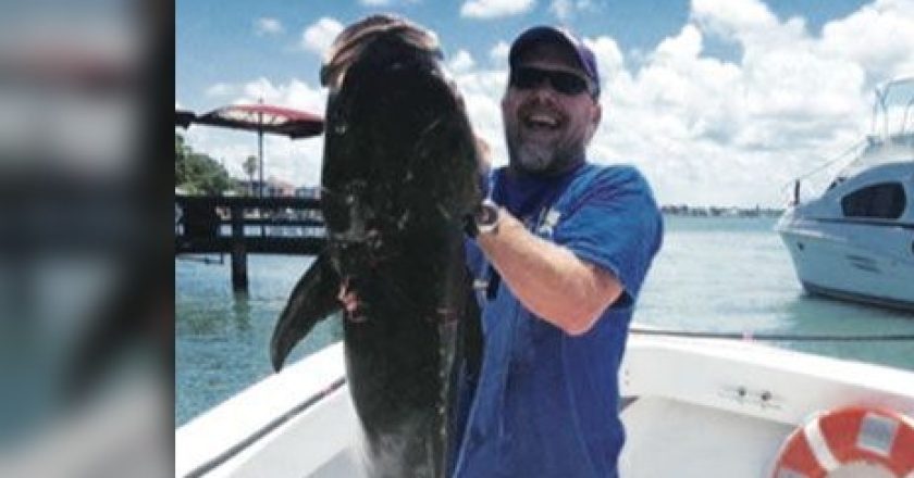 Angler holding a large fish on a boat