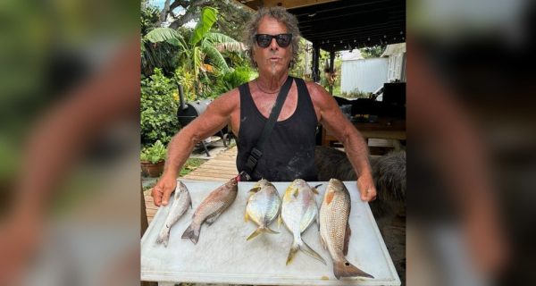 Angler with a cleaning table of pompano and other surf-caught fish