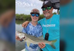 Young angler holding a snook alongside Captain Brian Gober of Rare Breed Charters