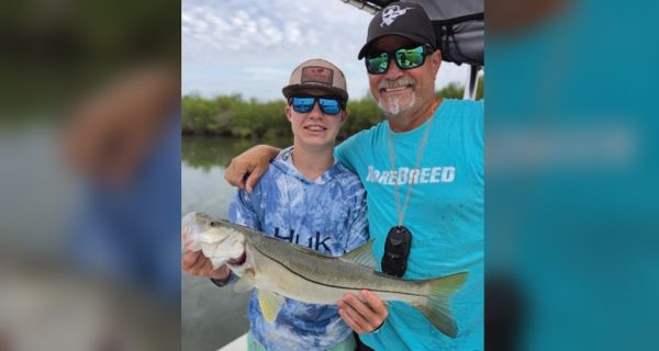 Young angler holding a snook alongside Captain Brian Gober of Rare Breed Charters