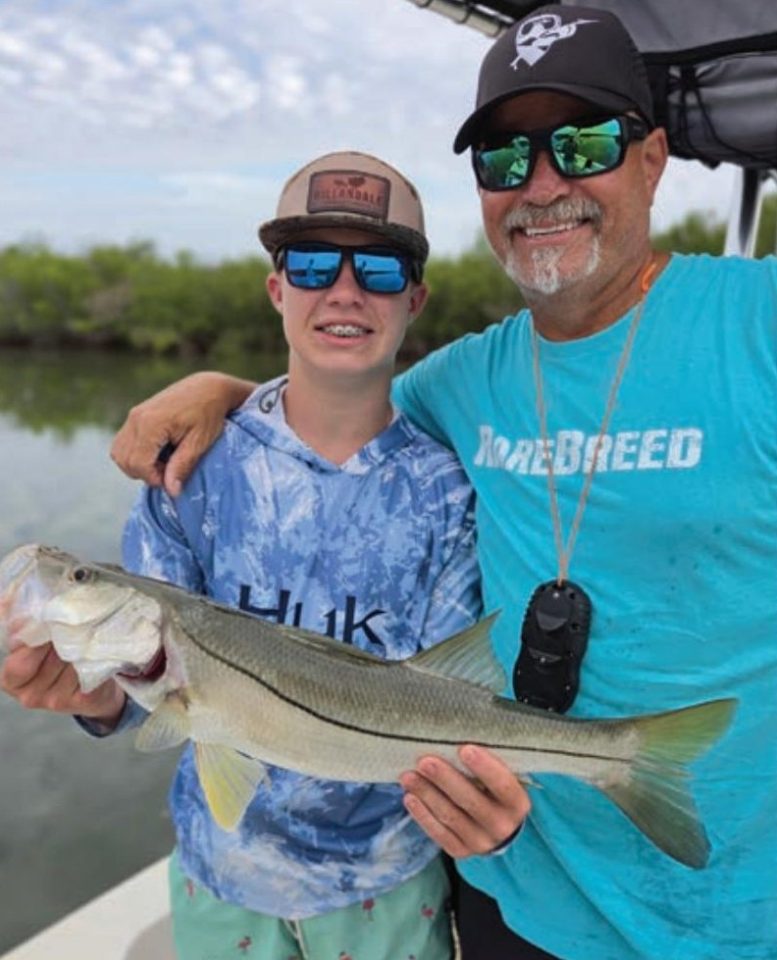 Young angler holding a snook alongside Captain Brian Gober of Rare Breed Charters