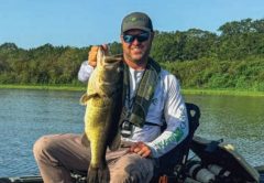 Tyler Bean holding a largemouth bass from his kayak on Kenansville Lake