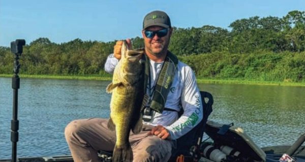 Tyler Bean holding a largemouth bass from his kayak on Kenansville Lake