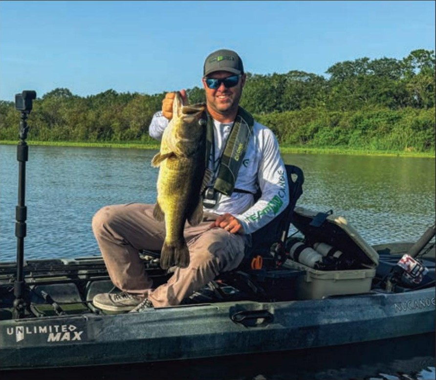 Tyler Bean holding a largemouth bass from his kayak on Kenansville Lake