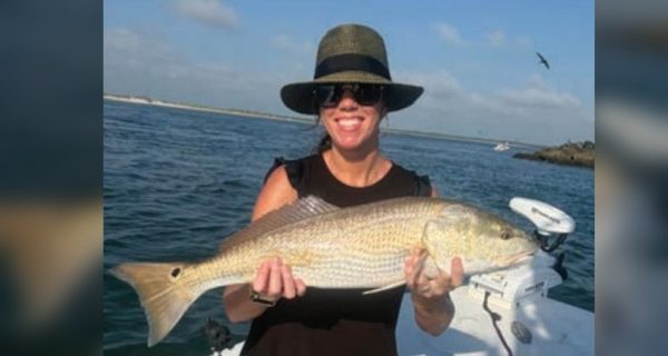 Angler holding a redfish on a Yellow Dawg Fishing charter near Ponce Inlet