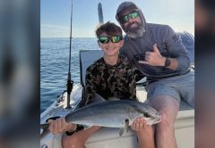 Youth angler holding an amberjack alongside Captain Evan Sanders of Sol Fishing